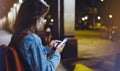 Woman with backpack pointing finger on blank screen smartphone on background bokeh light in night atmospheric city, blogger hipste Royalty Free Stock Photo