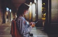 Woman with backpack pointing finger on blank screen smartphone on background bokeh light in night atmospheric city, blogger Royalty Free Stock Photo