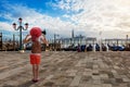 A woman with backpack and red sunhat stands alone on the St. Mark`s Square in Venice, Italy Royalty Free Stock Photo