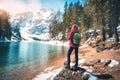 Woman with backpack on the stone near lake with azure water Royalty Free Stock Photo