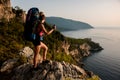 Woman with backpack on top of mountain enjoy view of beautiful sea landscape.