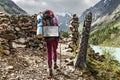 Woman with a backpack travels through an esoteric pagan stone town with a wooden idol in the mountains of the Altai