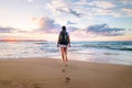 Woman with backpack walk on the ocean sand beach at sunset time Royalty Free Stock Photo