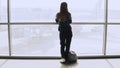 Woman with backpack walks to airport window. Happy successful European passenger girl with smartphone in terminal. 4K.