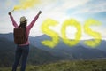 Woman with backpack and word SOS made of color smoke bomb in mountains, back view Royalty Free Stock Photo