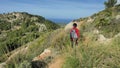 Woman backpacker hiking within mountain trek on Mallorka islan. Sunny spring day with comfortable temperature.