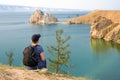 A woman backpacker looks at the Shamanka Rock, Cape Burhan on Olkhon Island in the evening Royalty Free Stock Photo