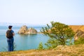 A woman backpacker looks at the Shamanka Rock, Cape Burhan on Olkhon Island. Lake Baikal, Russia Royalty Free Stock Photo