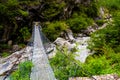 Woman backpacker on trekking path crossing a suspended bridge in Annapurna Conservation Area, Nepal