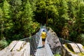 Woman backpacker on trekking path crossing a suspended bridge in Annapurna Conservation Area, Nepal