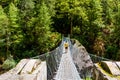 Woman backpacker on trekking path crossing a suspended bridge in Annapurna Conservation Area, Nepal