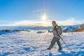 Woman backpacker trekking on snow on the Alps. Rear view, winter lifestyle, cold feeling, sun star in backlight, hiking poles. Royalty Free Stock Photo