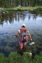 Woman backpacker wading across river Royalty Free Stock Photo