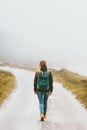 Woman backpacker walking alone on foggy road Royalty Free Stock Photo