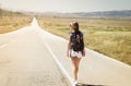 Woman backpacker walking on road Royalty Free Stock Photo