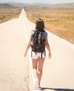 Woman backpacker walking on road Royalty Free Stock Photo