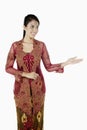 Woman in baju kebaya with welcoming hand gesture. Conceptual image