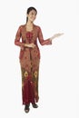 Woman in baju kebaya with welcoming hand gesture. Conceptual image