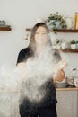 Woman baker clapping and sprinkling white flour over dough on kitchen background Royalty Free Stock Photo