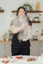 Woman baker clapping and sprinkling white flour over dough on kitchen background Royalty Free Stock Photo