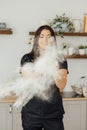 Woman baker clapping and sprinkling white flour over dough on kitchen background Royalty Free Stock Photo