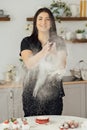 Woman baker clapping and sprinkling white flour over dough on kitchen background Royalty Free Stock Photo