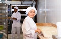 Woman baker dividing raw dough into portions in bakery