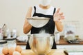 Woman baker sifting flour into mixing bowl. Royalty Free Stock Photo