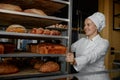 Woman baker smiling happily pushing rack with fresh baked bread Royalty Free Stock Photo