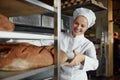 Baker smiling happily pushing rack with fresh baked bread Royalty Free Stock Photo