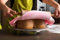 Woman in bakery decorating heart shaped cake with pink royal icing Royalty Free Stock Photo