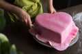 Woman in bakery decorating heart shaped wedding cake with pink fondant, view from above Royalty Free Stock Photo