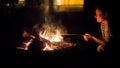 Woman bakes apple on bonfire