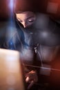 Woman in balaclava using laptop