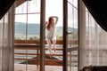 Woman on the balcony holding a cup of coffee ore tea in the morning. She in hotel room looking at the nature in sumer Royalty Free Stock Photo