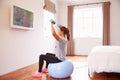 Woman On Ball Working Out To Fitness DVD On TV In Bedroom Royalty Free Stock Photo