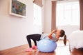 Woman On Ball Working Out To Fitness DVD On TV In Bedroom Royalty Free Stock Photo