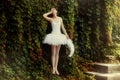 Woman ballerina in a white dress is standing in a sensual pose.