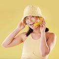 Woman, banana phone call and studio with smile, communication and eyes sticker art on face. Asian model girl, yellow
