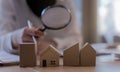 Woman bank officer or appraiser using magnifying glass to check miniatures house model. Royalty Free Stock Photo