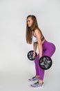 woman with a barbell in her hands flexing her muscles in gym against a white wall background. Royalty Free Stock Photo