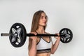 woman with a barbell in her hands flexing her muscles in gym against a white wall background. Royalty Free Stock Photo