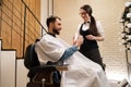 Woman in a barbershop demonstrates skin care products to client