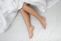 Woman bare feet covered with bright blanket on mattress of bed in bedroom in comfortable conditions Royalty Free Stock Photo