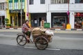 Woman in bare feet transports goods with an old, rusted tricycle Singapore