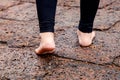 Woman bare feet walking on wet rocky pavement