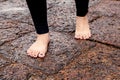 Woman bare feet walking on wet rocky pavement