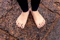 Woman bare feet on wet rocky pavement