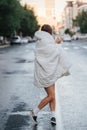 Woman wrapped in blanket walking across empty city road early in the morning Royalty Free Stock Photo