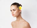 woman with bare shoulders cosmetics flower behind ear cropped view light background Royalty Free Stock Photo